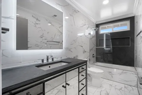 a bathroom with a sink a toilet a mirror and shower