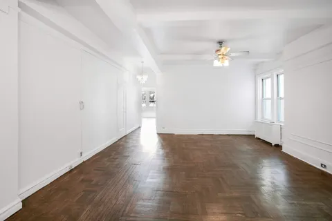 an empty room with wooden floor and ceiling fan