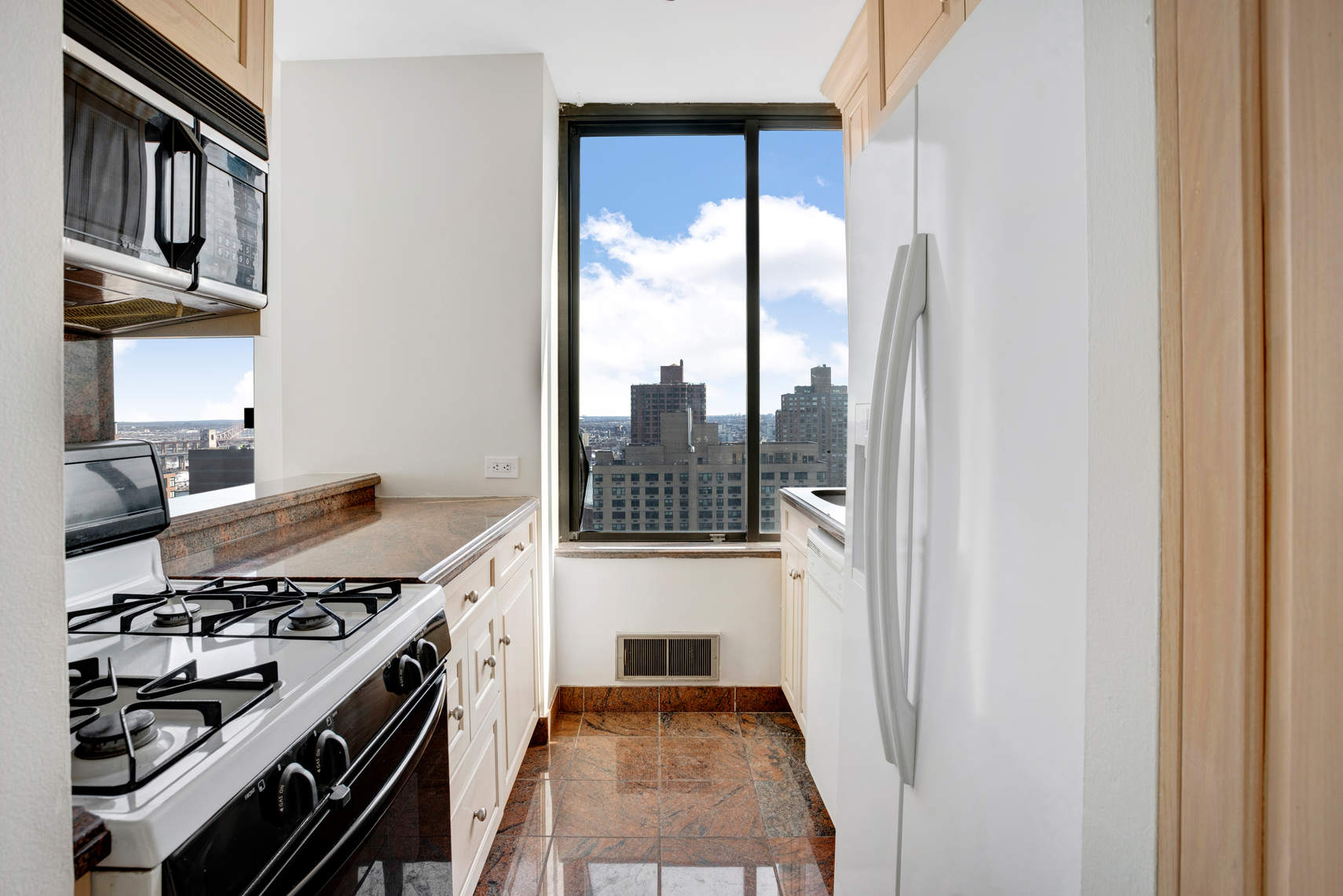 300 East 93rd Street, Unit 35D Manhattan, NY 10128 - Photo 3 of 13 a kitchen with a stove a refrigerator and a wooden floor