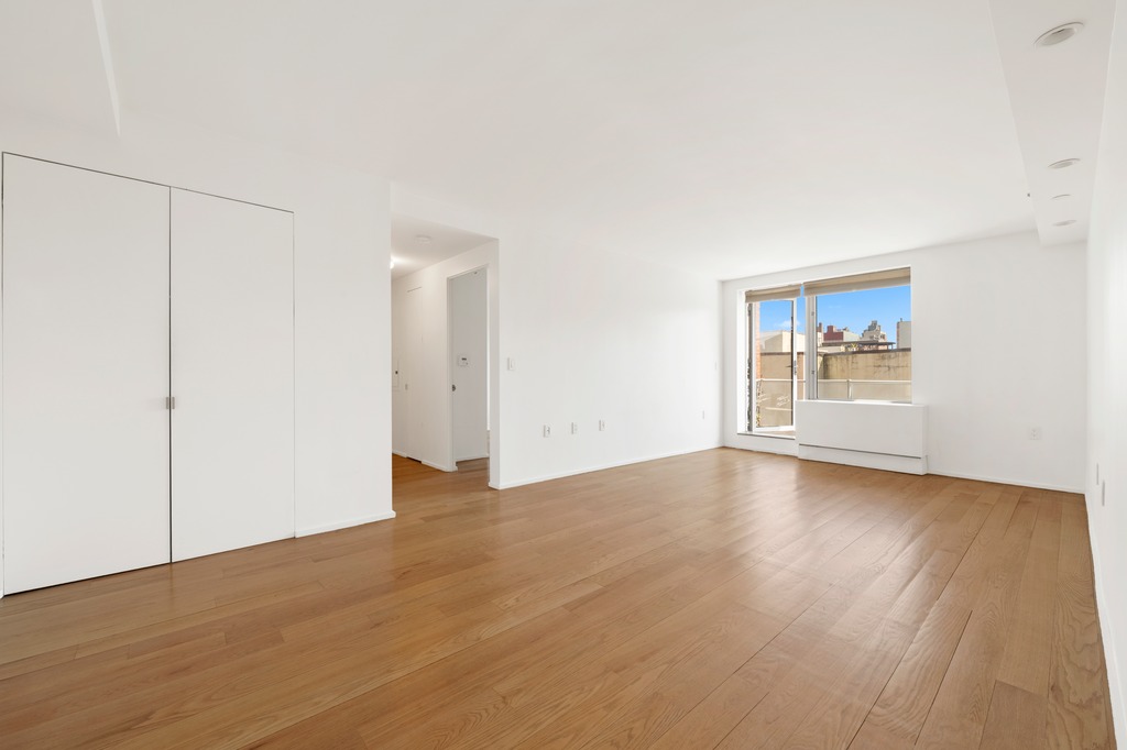 2280 Frederick Douglass Boulevard, Unit 6A Manhattan, NY 10027 - Photo 11 of 13 a view of an empty room with wooden floor and a window