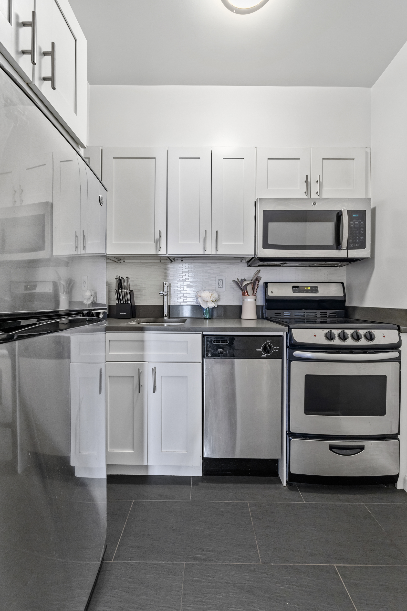 80 Park Avenue, Unit 11D Manhattan, NY 10016 - Photo 5 of 7 a kitchen with stainless steel appliances granite countertop a stove a sink and a microwave