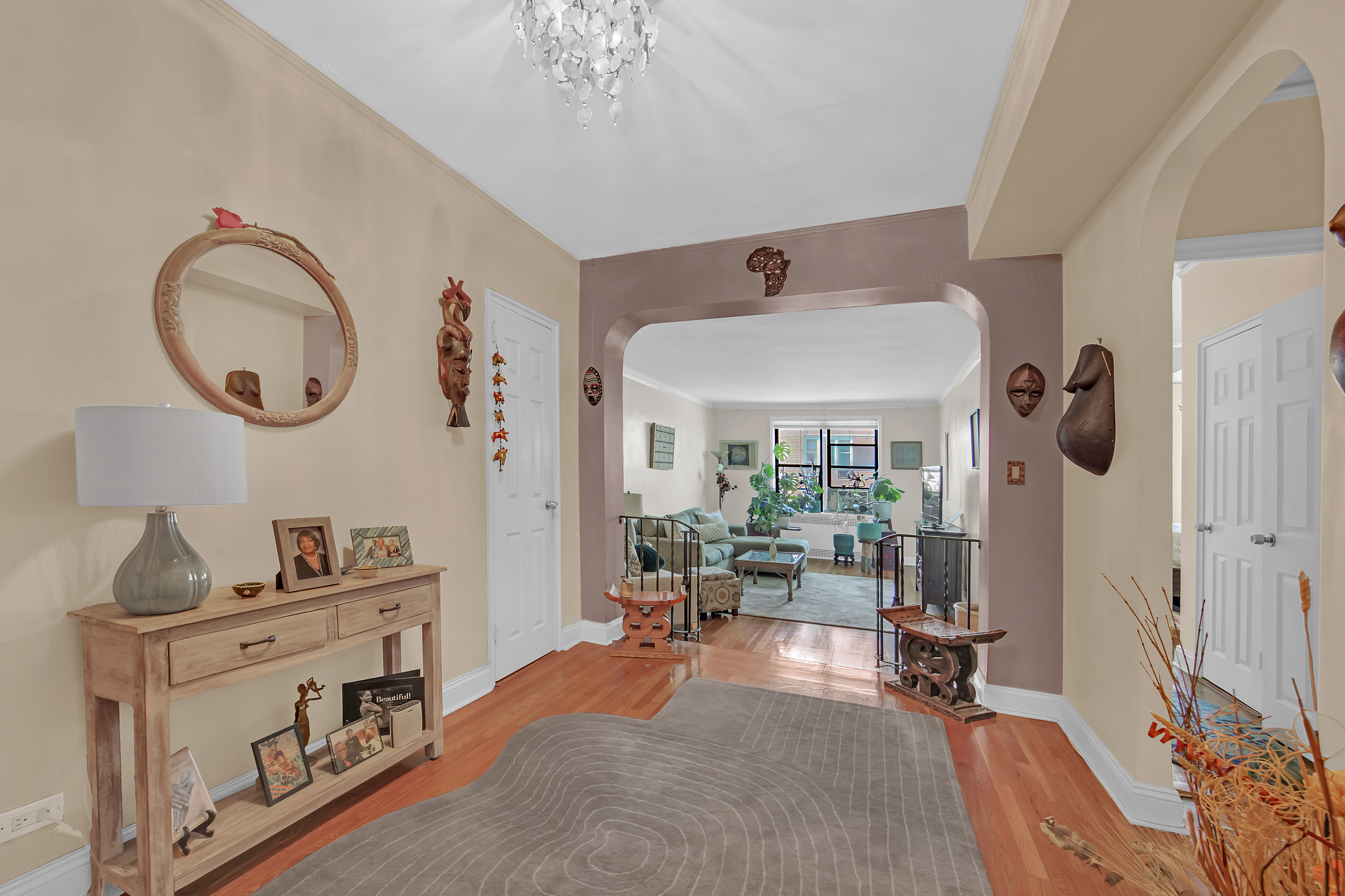 55 East 190th Street, Unit 59 Bronx, NY 10468 - Photo 3 of 14 a living room with furniture a chandelier and a large mirror next to a window