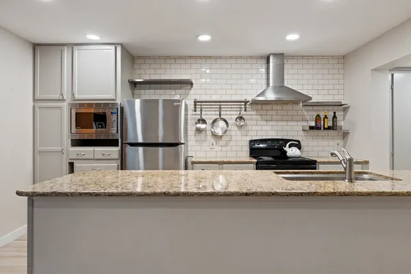 a kitchen with stainless steel appliances granite countertop a refrigerator a stove and a sink