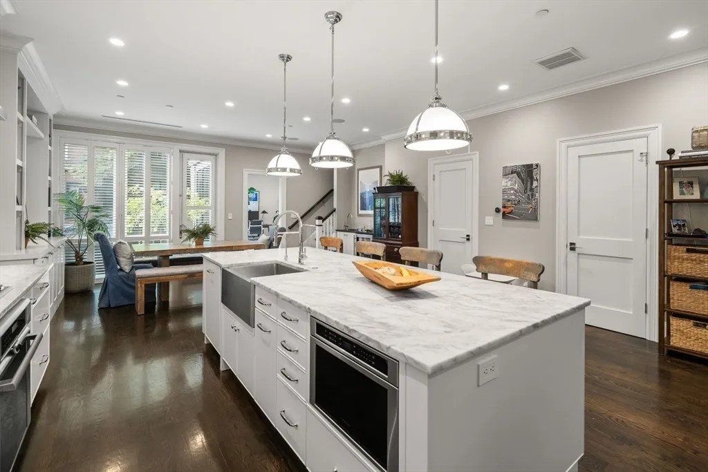 a kitchen with a stove a sink a kitchen island with wooden cabinets and couches