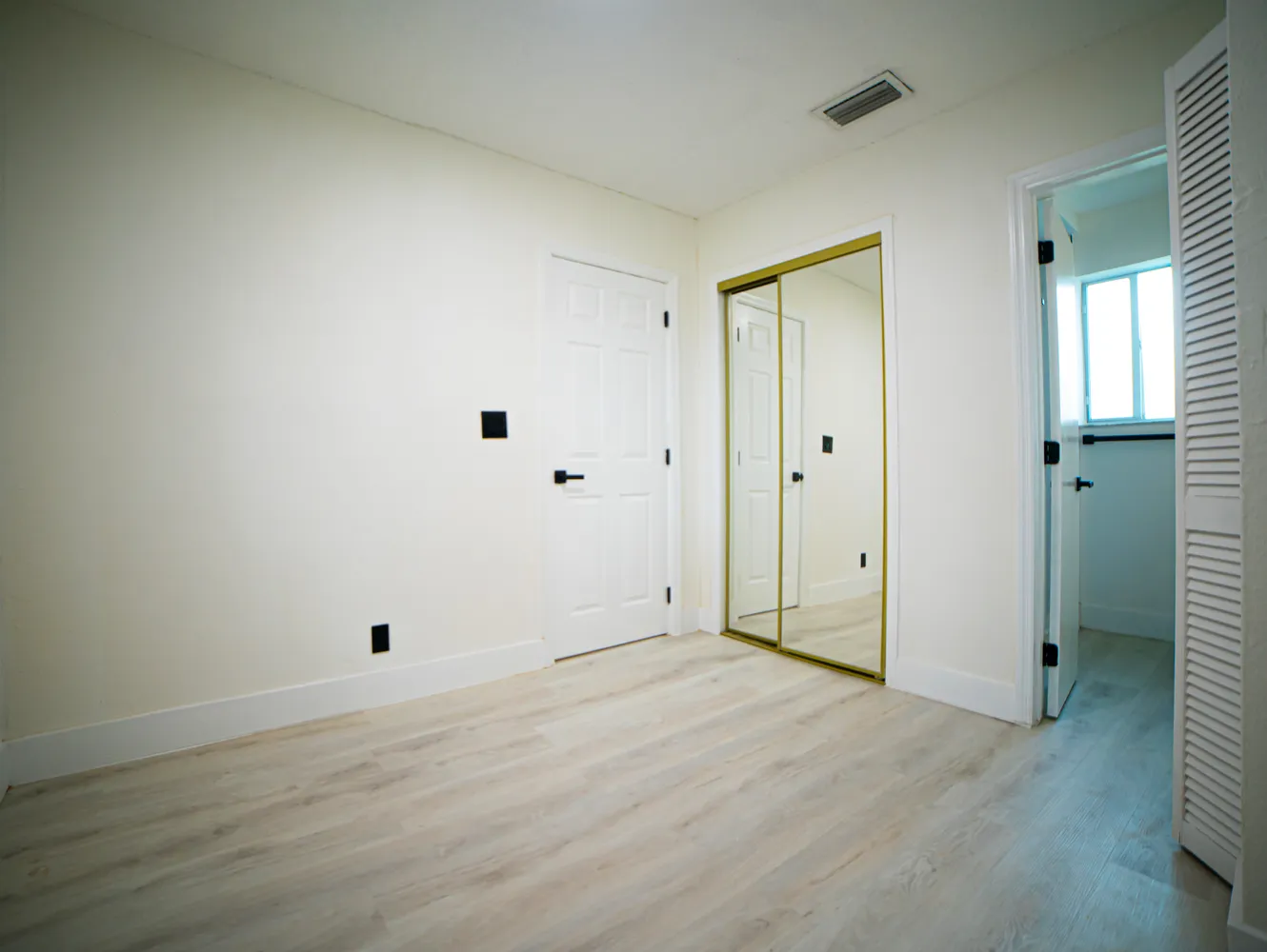 an empty room with wooden floor and window
