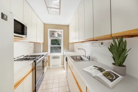a kitchen with stainless steel appliances a sink a stove cabinets and a window