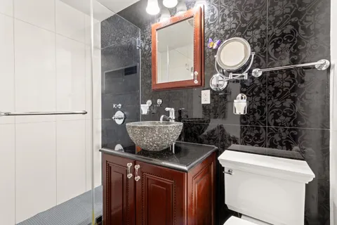 a bathroom with a granite countertop sink a toilet and a mirror