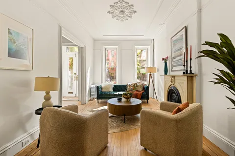 a living room with furniture a fireplace and a potted plants next to a window