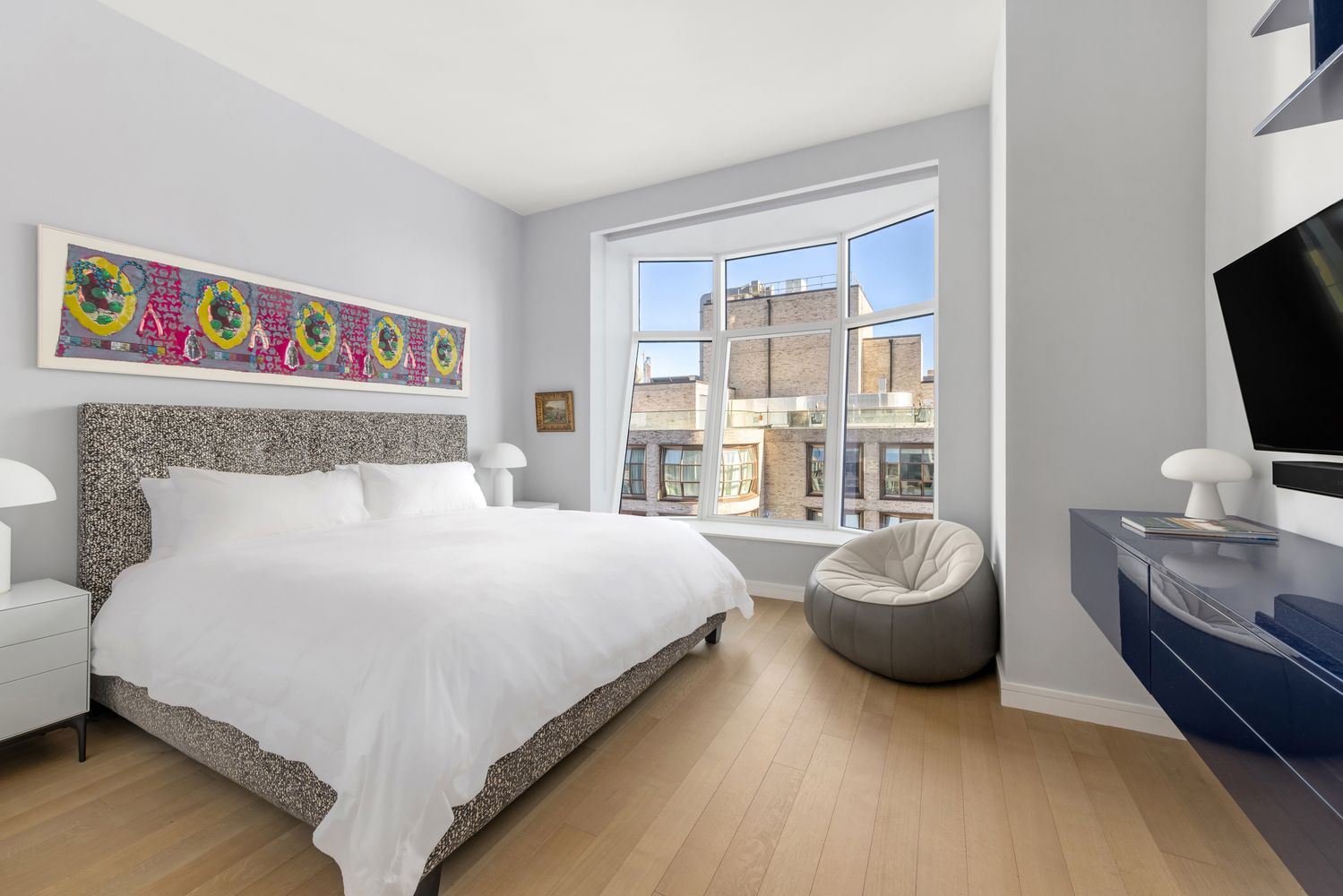 a bedroom with a bed and a flat tv screen on dresser
