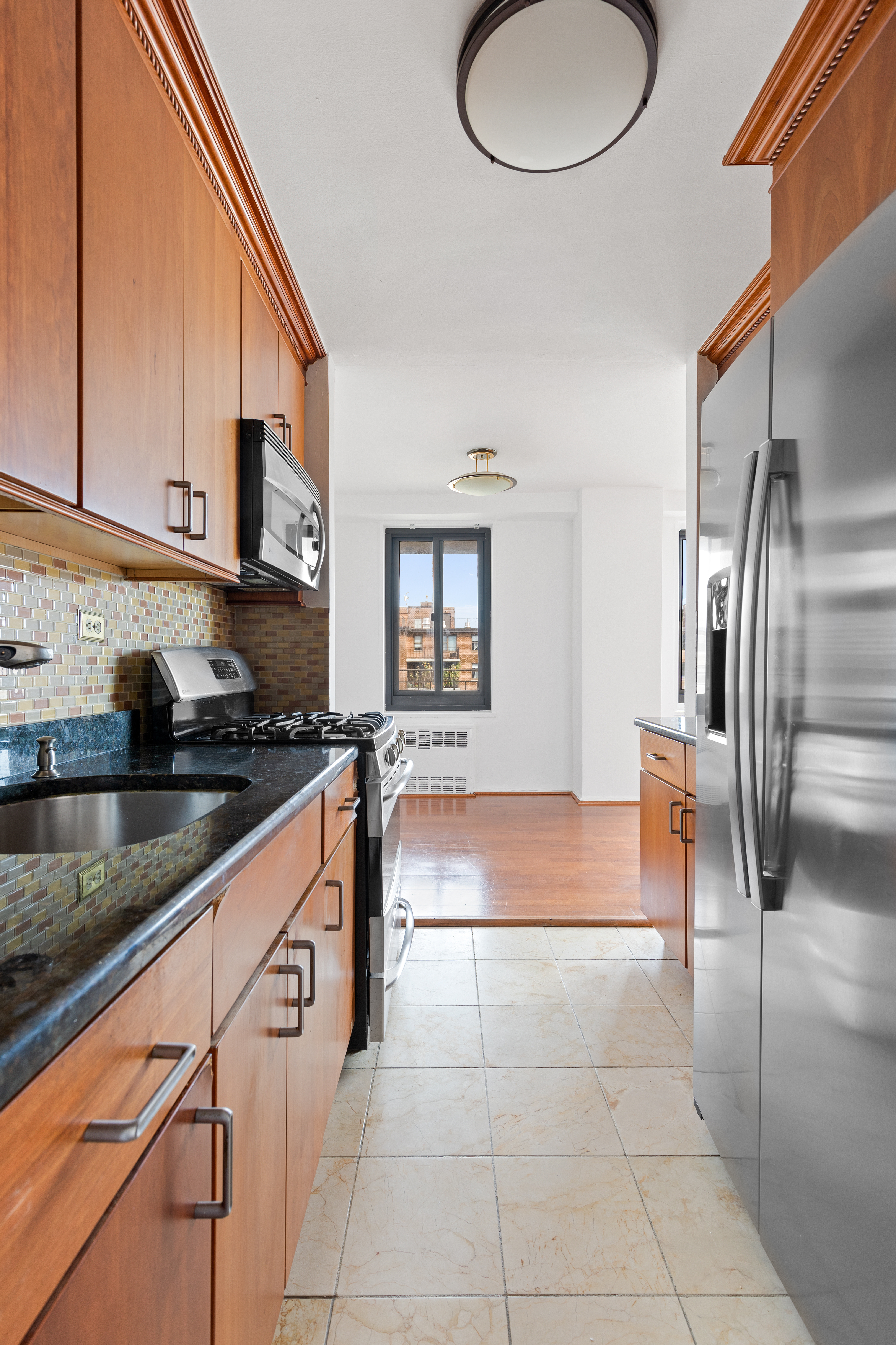 195 Willoughby Avenue, Unit 1612 Brooklyn, NY 11205 - Photo 5 of 10 a kitchen with stainless steel appliances granite countertop a sink and a refrigerator