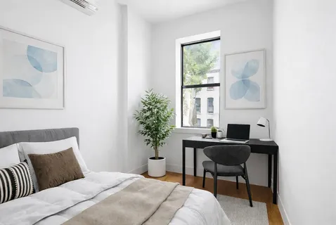 a bedroom with a bed table chair and a window