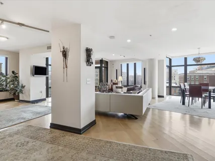 a large white kitchen with kitchen island a refrigerator a stove a sink a dining table and chairs with wooden floor