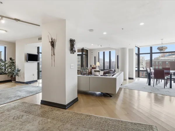 a large white kitchen with kitchen island a refrigerator a stove a sink a dining table and chairs with wooden floor