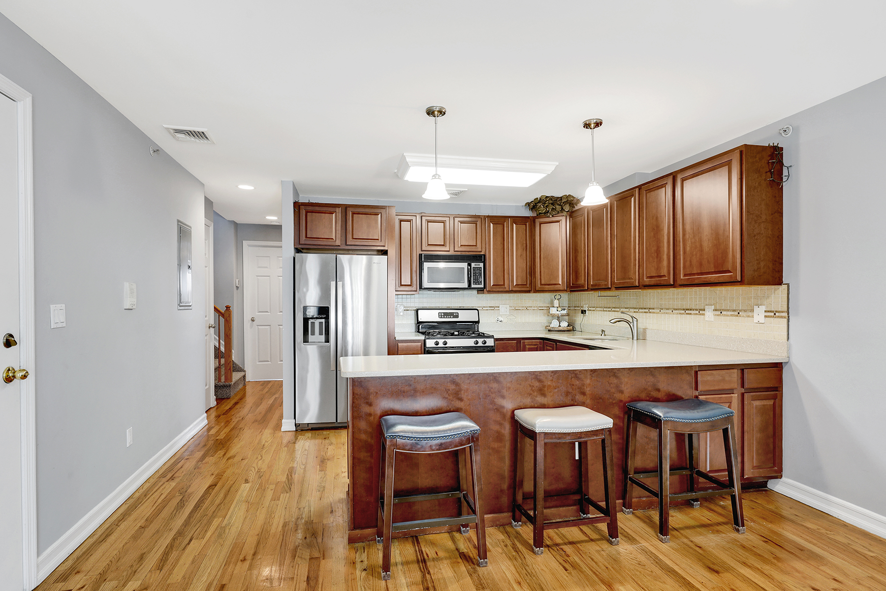 10220 Rockaway Beach Boulevard, Unit 3C Queens, NY 11694 - Photo 13 of 46 a kitchen with a table chairs refrigerator and wooden cabinets