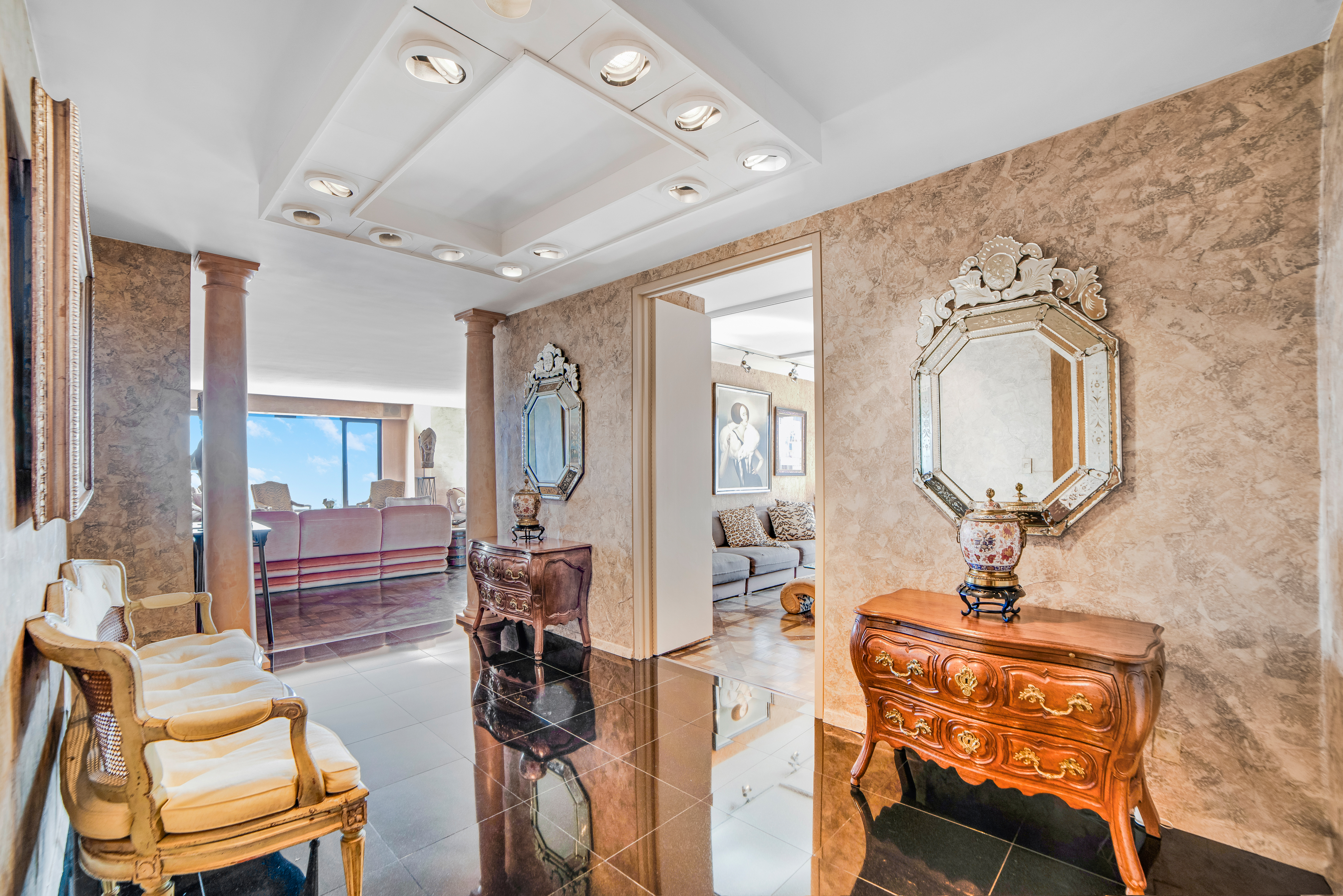 200 Central Park South, Unit 24A Manhattan, NY 10019 - Photo 9 of 23 a living room with furniture a large mirror and a chandelier