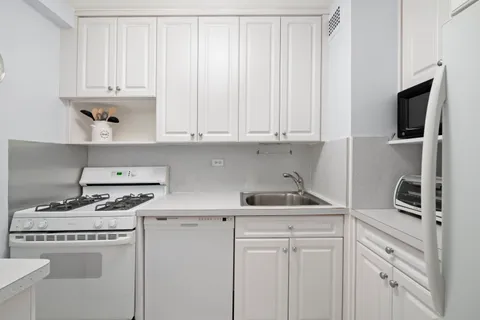 a kitchen with white cabinets and a stove a sink