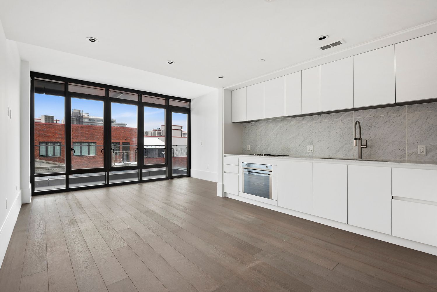 429 Kent Avenue, Unit 912 Brooklyn, NY 11249 - Photo 2 of 11 a view of a kitchen with stainless steel appliances wooden floor and a large window