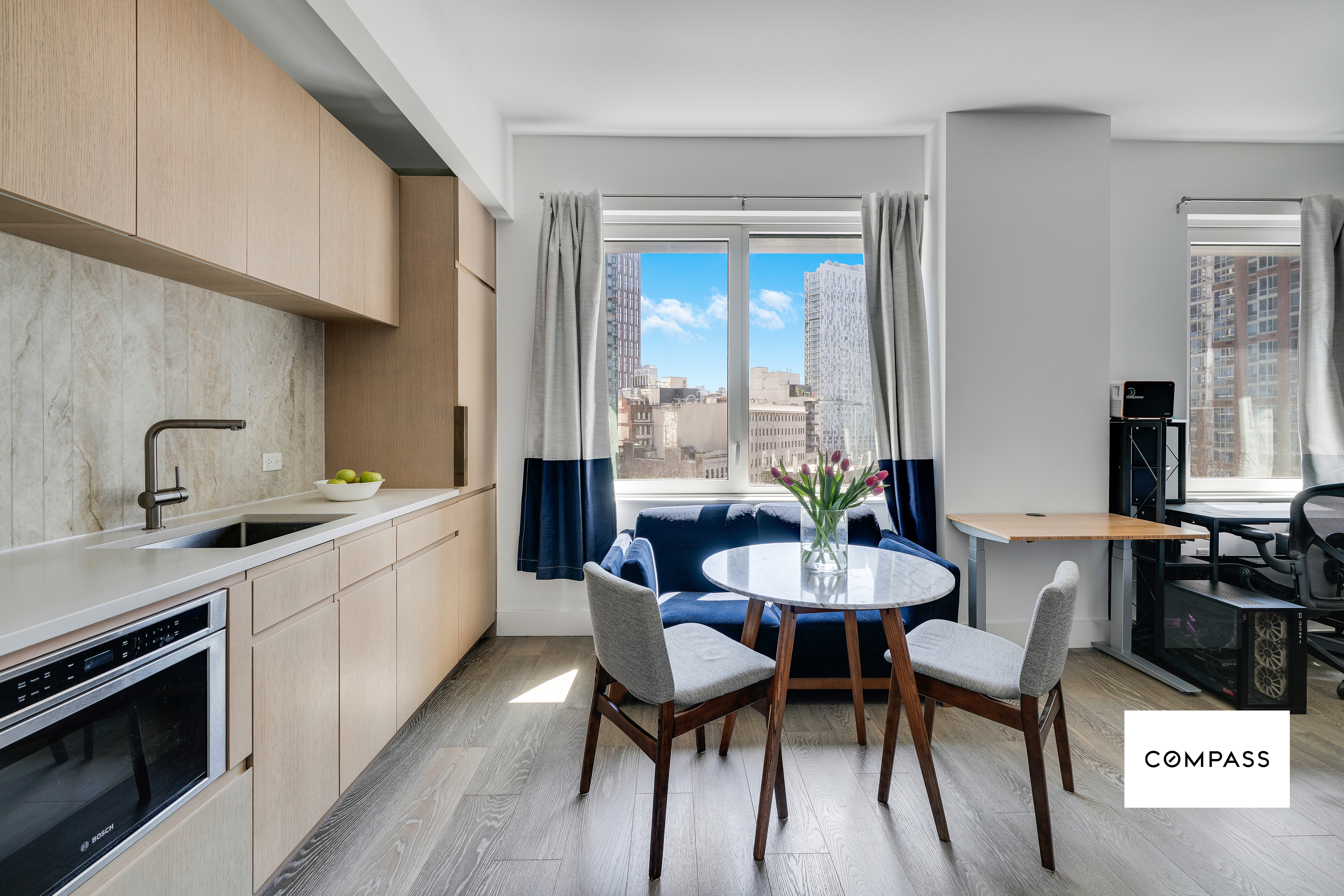 10 Nevins Street, Unit 14E Brooklyn, NY 11217 - Photo 1 of 11 a kitchen with stainless steel appliances a dining table chairs and a wooden floor