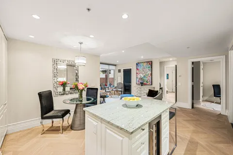 a view of a dining room and livingroom with furniture wooden floor a rug a flat screen tv a painting and a chandelier