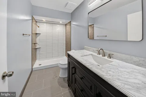 a bathroom with a granite countertop sink a toilet and shower
