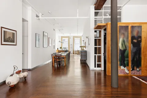 a dining room with wooden floor a chandelier a glass table and chairs