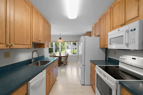 a kitchen with granite countertop a sink a stove and refrigerator