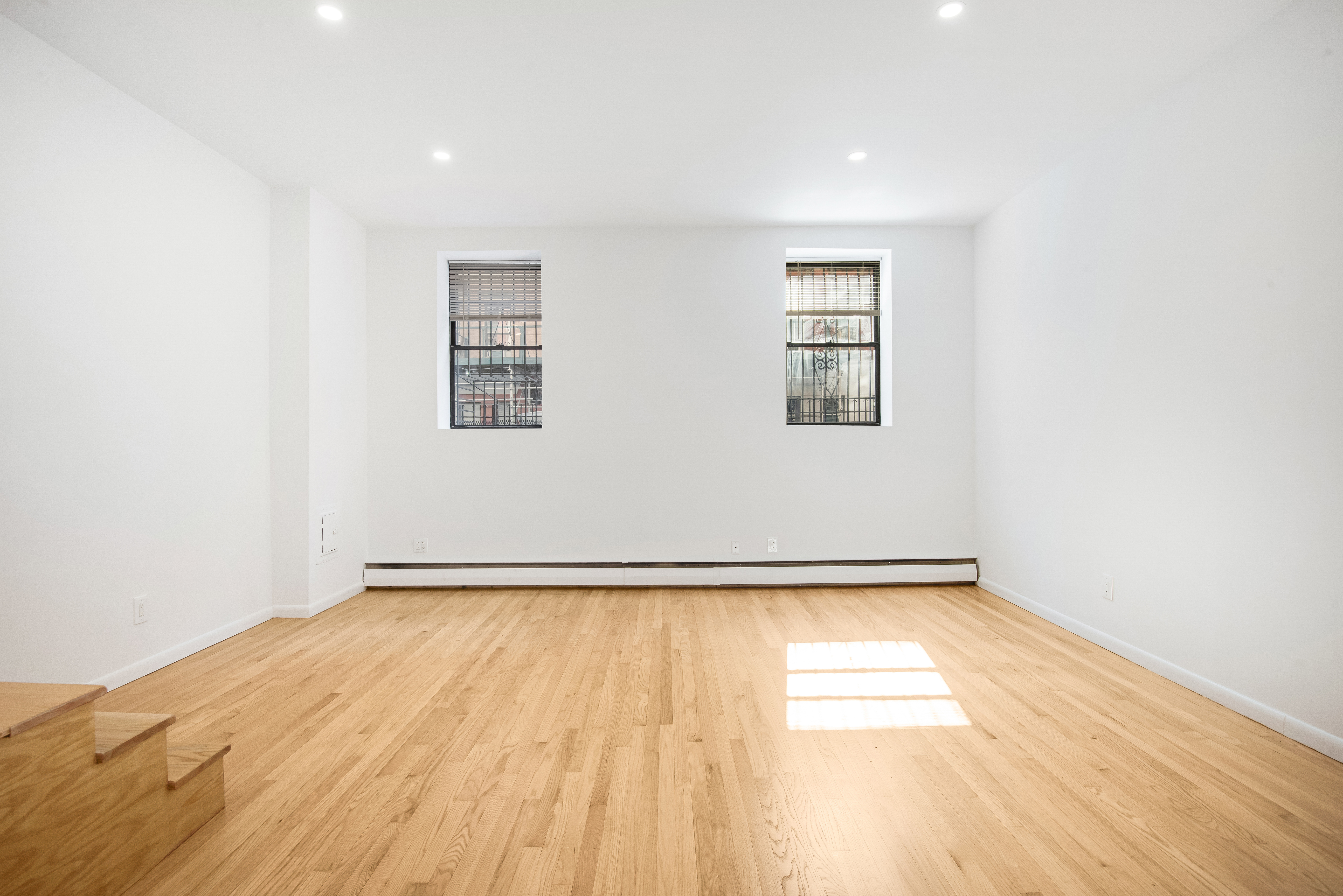 182 East 2nd Street, Unit 1E Manhattan, NY 10009 - Photo 5 of 14 an empty room with wooden floor and windows
