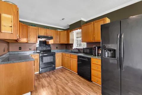 a kitchen with granite countertop a refrigerator stove top oven and sink