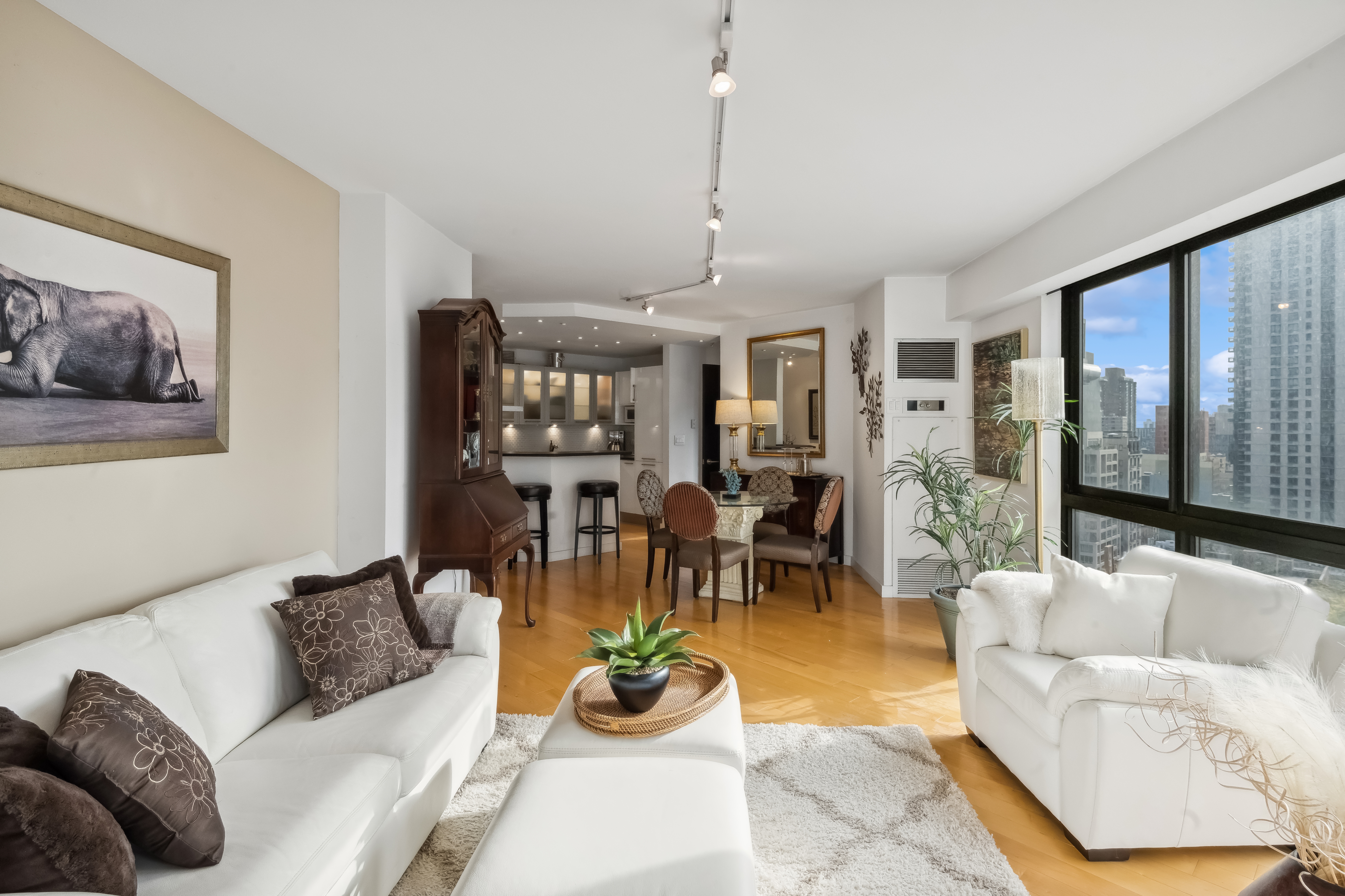 200 East 61st Street, Unit 18A Manhattan, NY 10065 - Photo 2 of 9 a living room with furniture a chandelier and a dining table