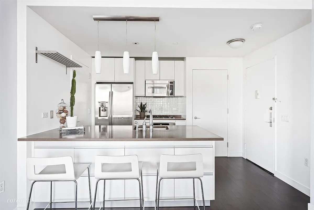 a kitchen with stainless steel appliances granite countertop a kitchen island and chairs in it