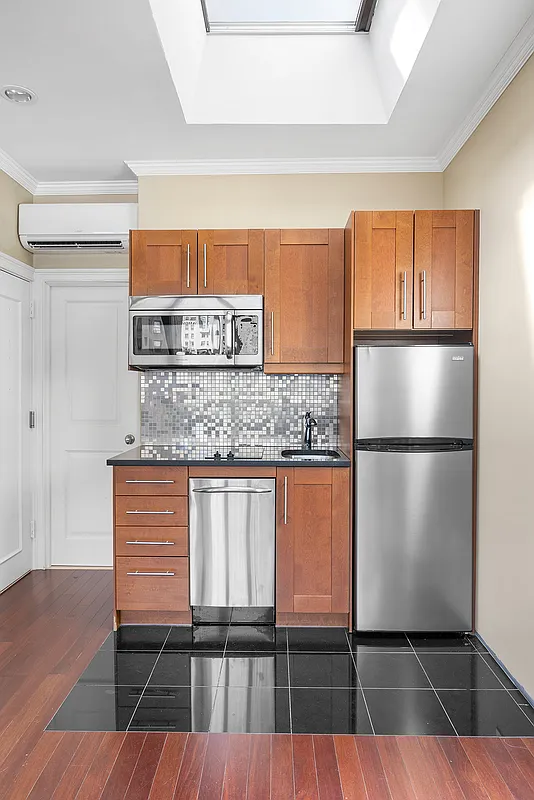 258 West 71st Street, Unit 3A Manhattan, NY 10023 - Photo 3 of 8 a kitchen with kitchen island a counter top space cabinets and a refrigerator