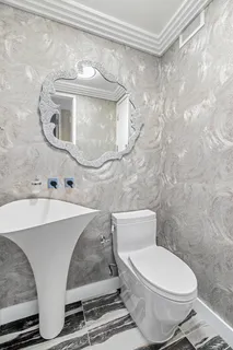 a white toilet sitting next to a bathroom sink and a mirror