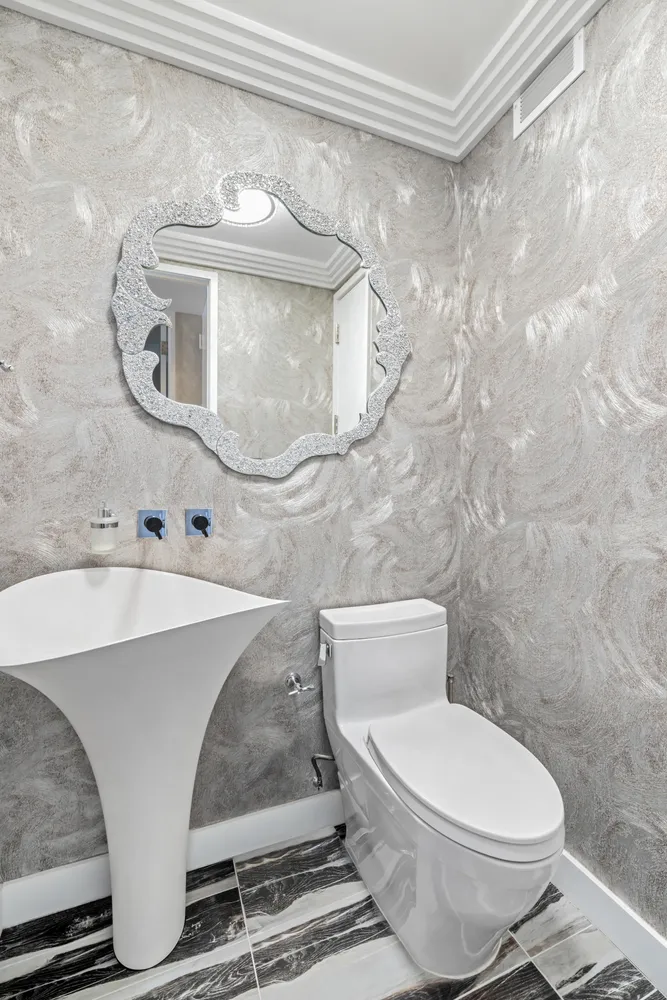 a white toilet sitting next to a bathroom sink and a mirror