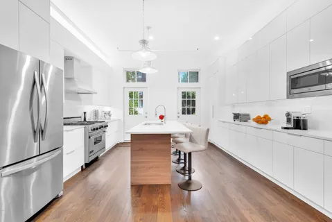 a kitchen with stainless steel appliances a refrigerator a stove a sink dishwasher and a dining table with wooden floor