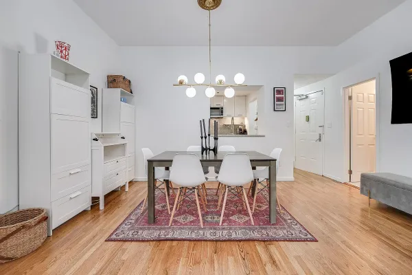 a dining room with wooden floor a chandelier a wooden table and chairs