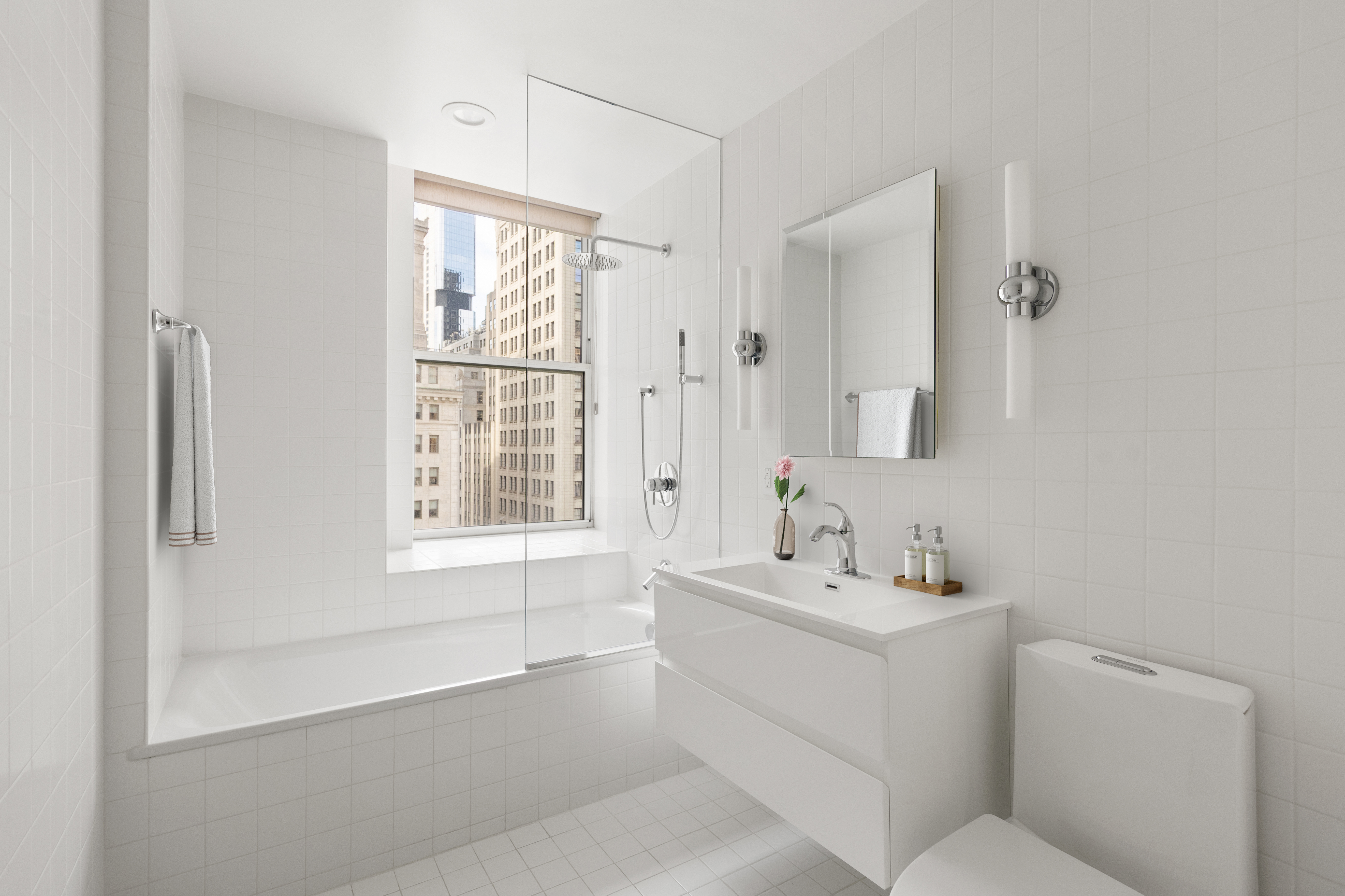 15 Broad Street, Unit 1900 Manhattan, NY 10005 - Photo 12 of 29 a bathroom with a sink toilet vanity and tub