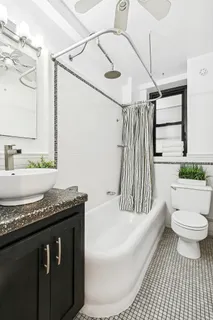 a bathroom with a granite countertop sink a toilet a mirror and bathtub