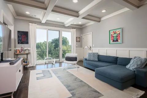a living room with furniture a flat screen tv and a floor to ceiling window