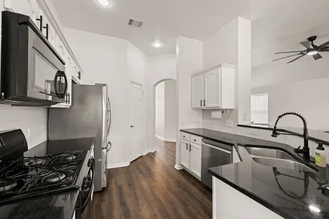 a kitchen with stainless steel appliances granite countertop a sink stove refrigerator and cabinets