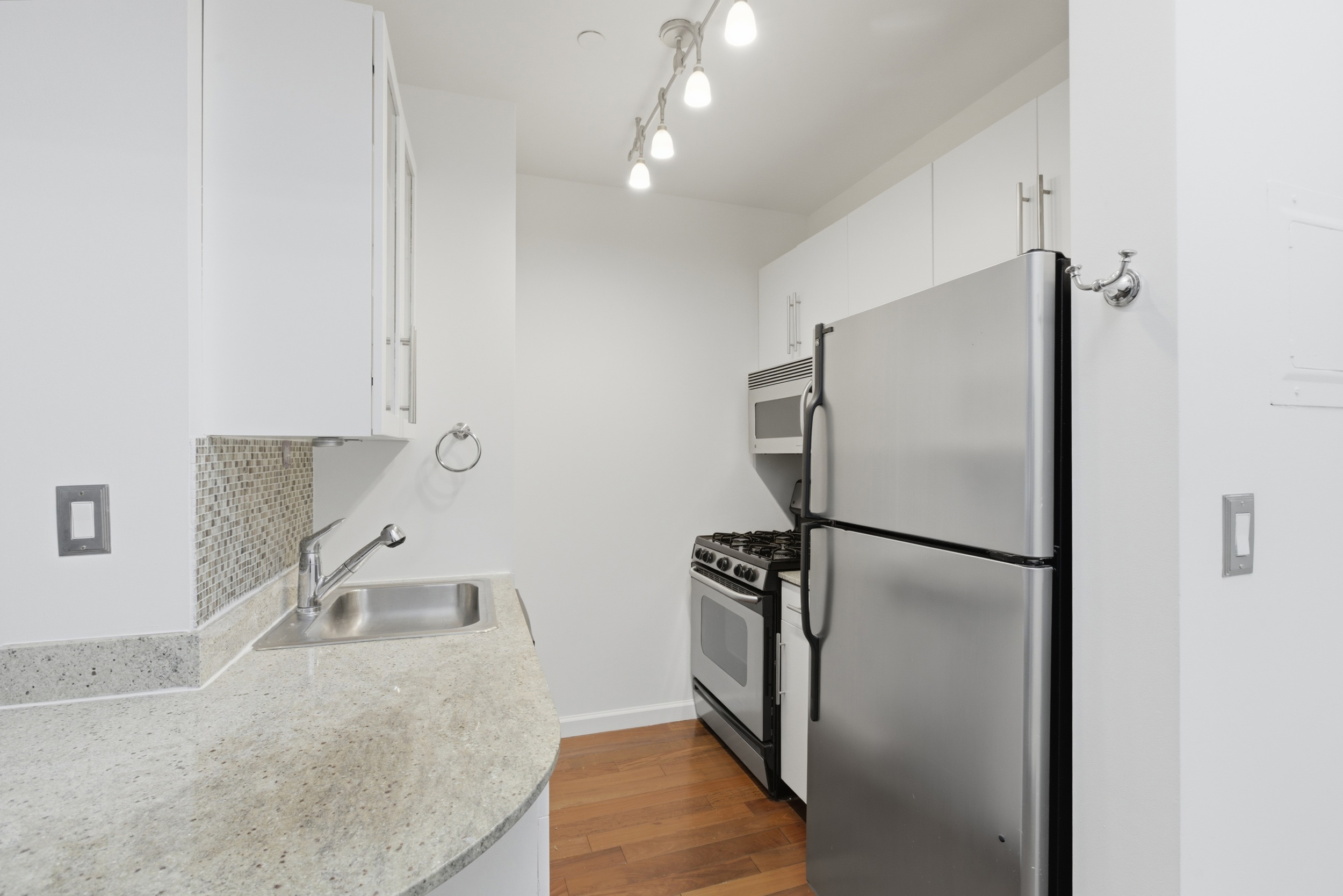 1 Wall Street Court, Unit 406 Manhattan, NY 10005 - Photo 5 of 7 a kitchen with a refrigerator and a sink