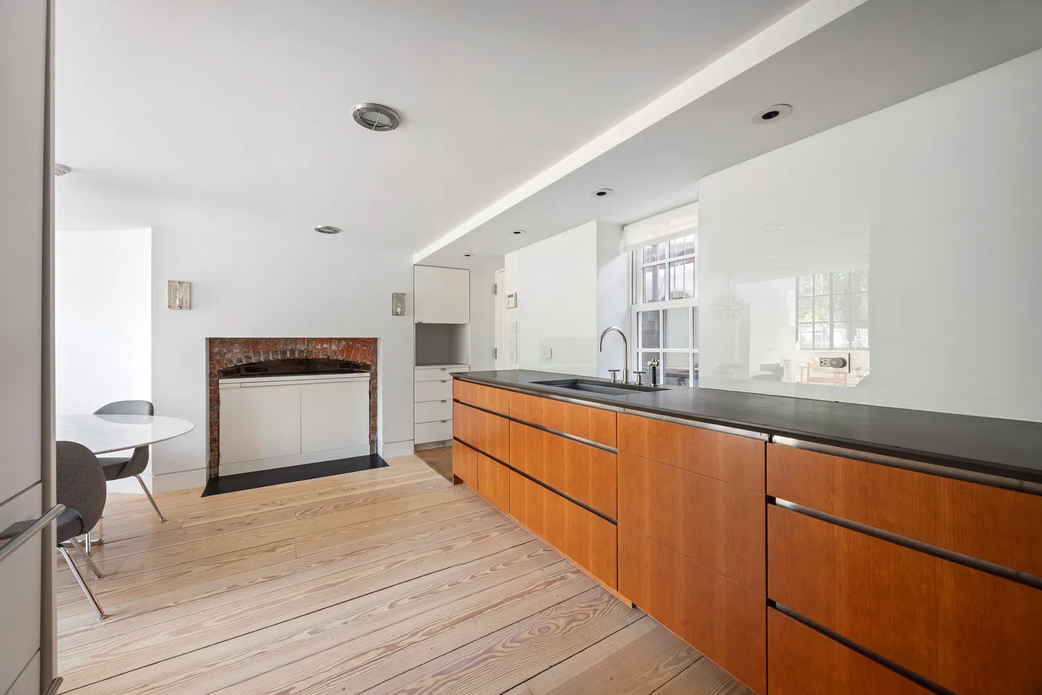 a large white kitchen with granite countertop a sink and dishwasher a stove with wooden floor