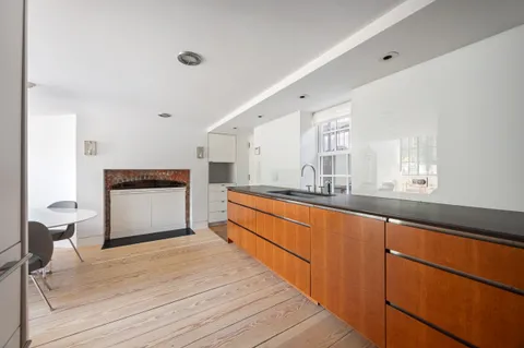 a large white kitchen with granite countertop a sink and dishwasher a stove with wooden floor