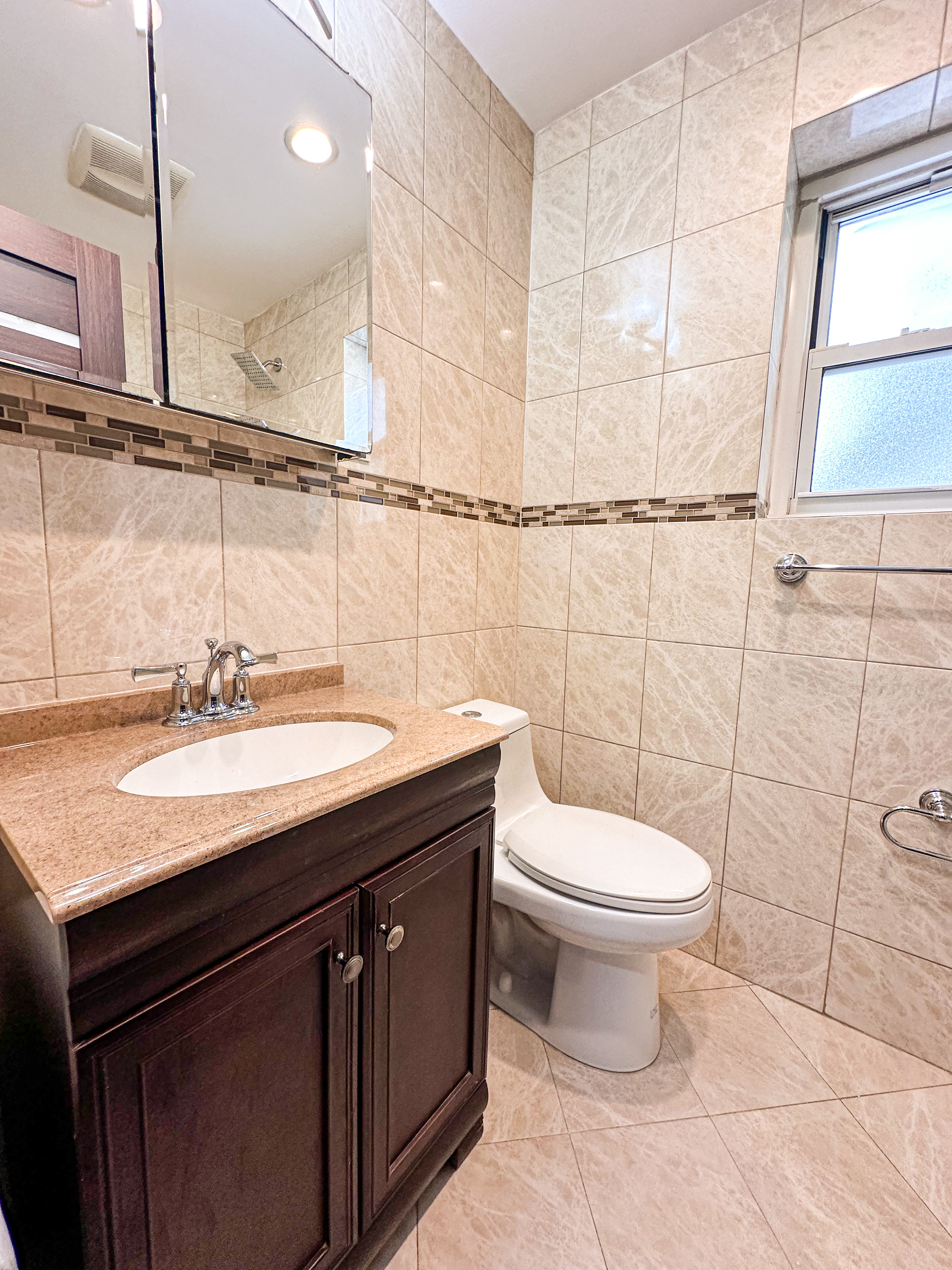 10-01 154th Street, Unit 1 Queens, NY 11357 - Photo 3 of 10 a bathroom with a granite countertop sink a toilet and a mirror