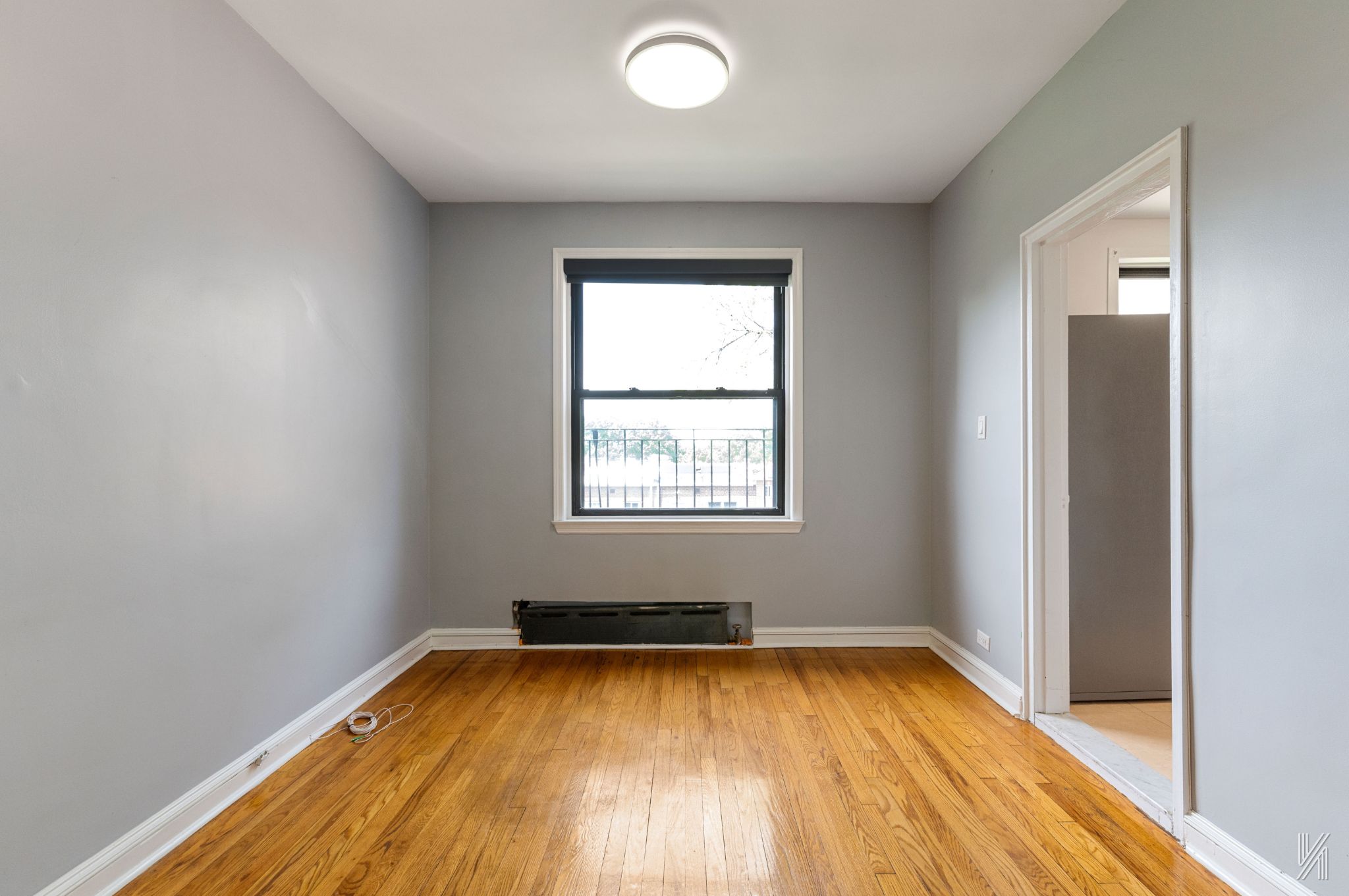 22-20 76th Street, Unit C3 Queens, NY 11370 - Photo 9 of 20 an empty room with wooden floor and windows