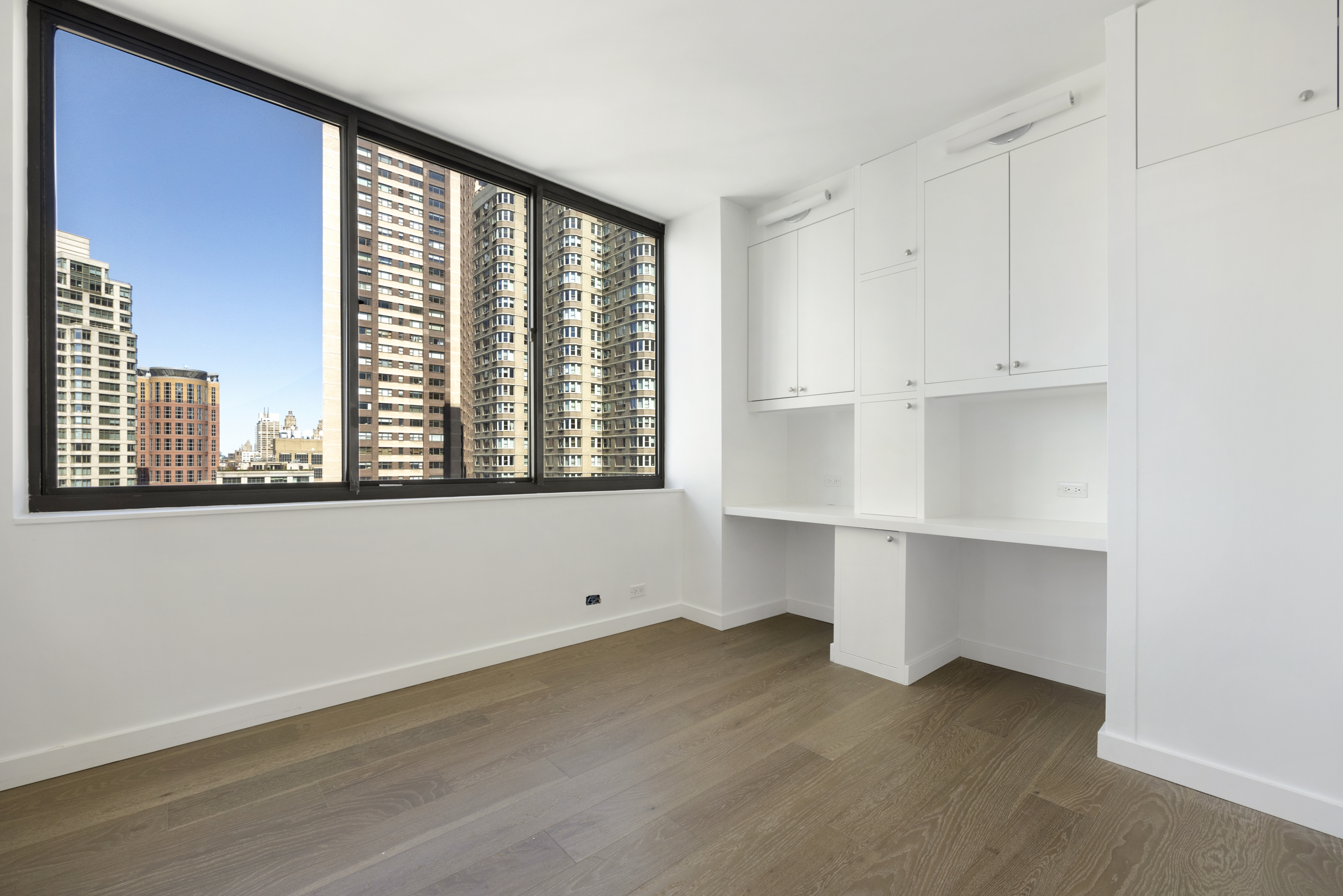 62 West 62nd Street, Unit 18A Manhattan, NY 10023 - Photo 4 of 16 a view of an empty room with wooden floor and a window