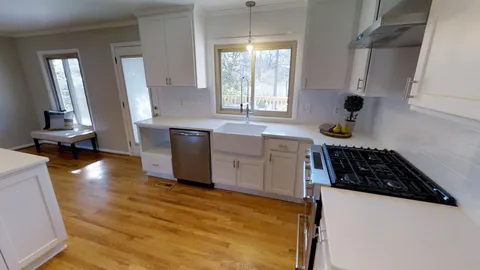 a kitchen with granite countertop a stove a sink a refrigerator and wooden floor