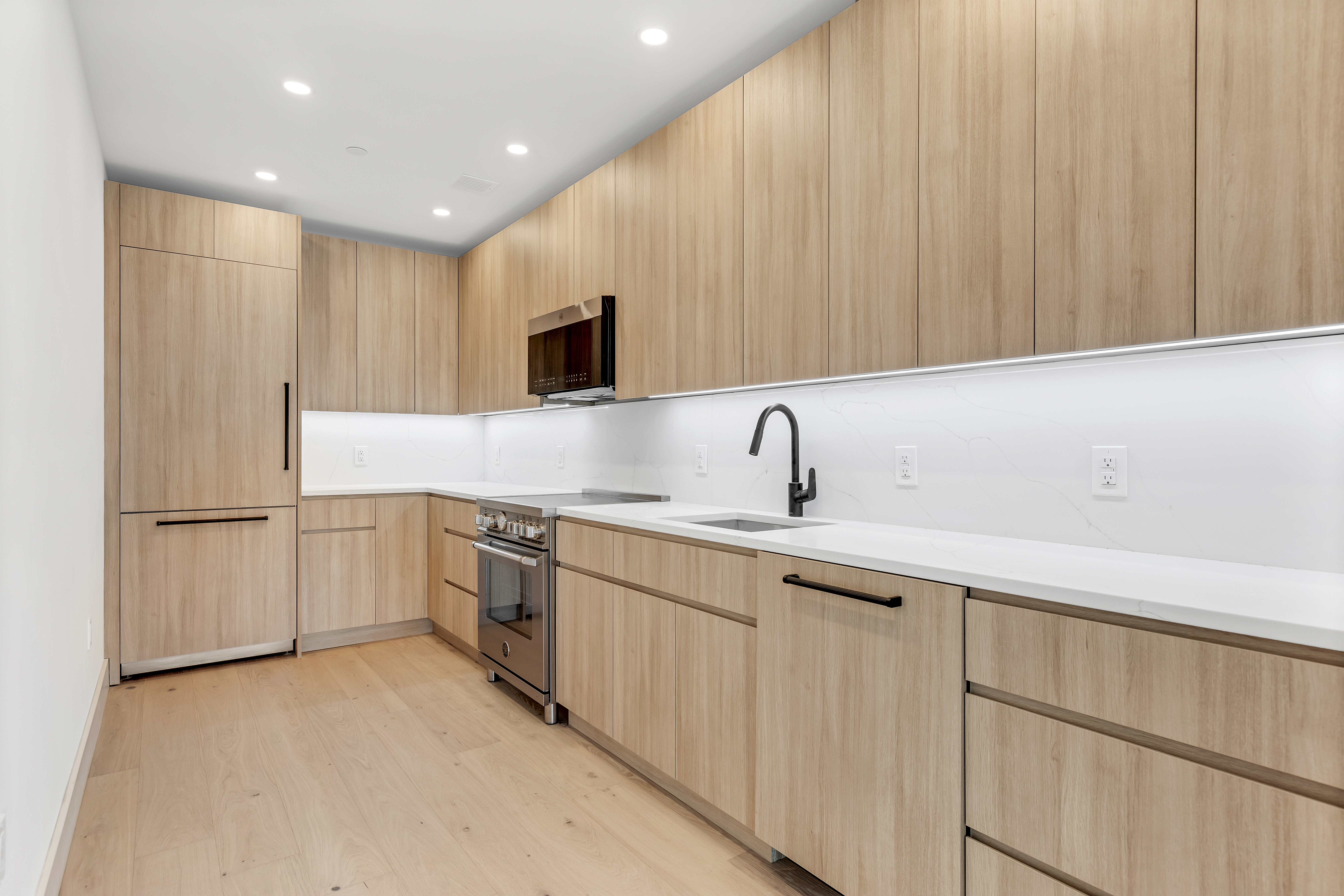 12-16 30th Avenue, Unit 201 Queens, NY 11102 - Photo 4 of 18 a kitchen with a sink cabinets and stainless steel appliances