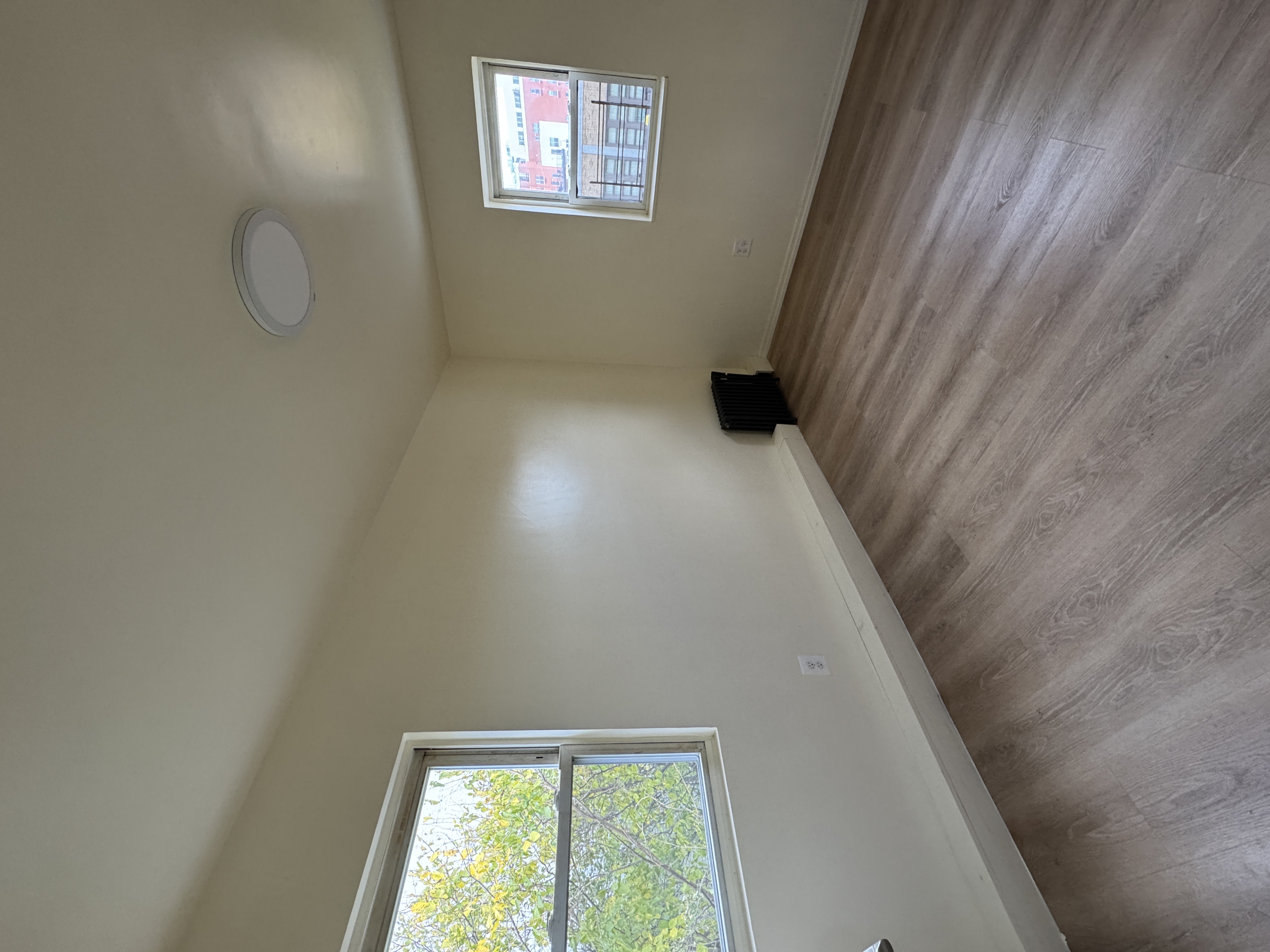 1333 Bristow Street Bronx, NY 10459 - Photo 6 of 6 an empty room with wooden floor and windows