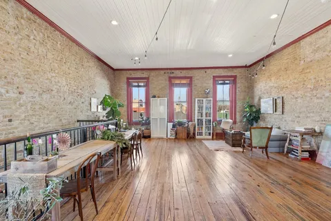 a living room with stainless steel appliances granite countertop furniture wooden floor and a large window