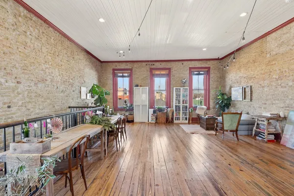 a living room with stainless steel appliances granite countertop furniture wooden floor and a large window